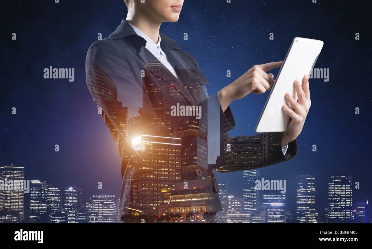 Donna d'affari che usa un tablet. Concetto a doppia esposizione con città notturna e donna in costume da lavoro. Investimenti immobiliari. Tecnologia digitale in Foto Stock