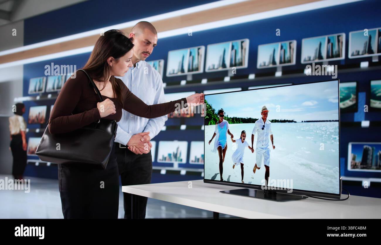 Il venditore di Smart TV fornisce consigli esperti alla giovane coppia Foto Stock