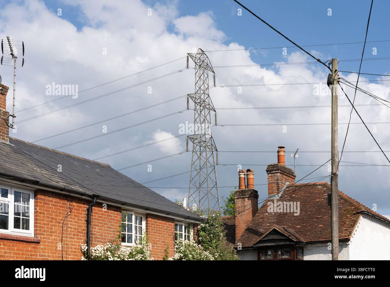 Cavi elettrici ad alta tensione e pilone vicino all'alloggiamento a Old Basing, Basingstoke, Regno Unito. Concetto: Salute umana, effetti sulla salute, linee aeree Foto Stock