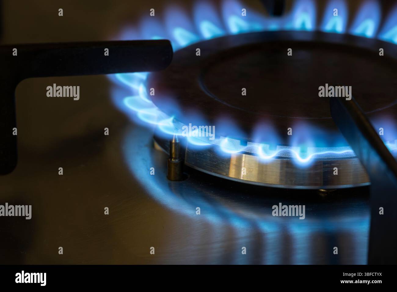Primo piano di una fiamma blu a gas naturale su un piano cottura, Regno Unito. Concetto: Costo della vita, limite energetico, pagamenti per il carburante invernale, energia del Regno Unito, bolletta del gas, bollette energetiche Foto Stock