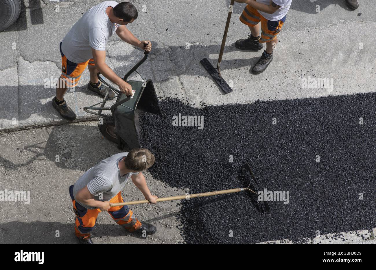 Operai, asfalto, superficie stradale, uomini. Carriola, rastrello, scopa Foto Stock