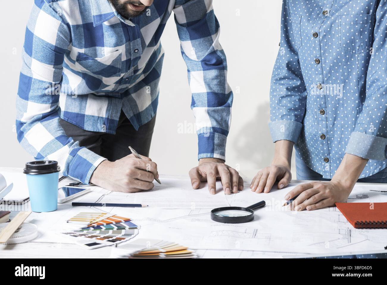 Uomo che scrive con penna su disegno tecnico. Team creativo di designer che lavorano insieme al progetto di costruzione. Studio approfondito e approvazione del des Foto Stock