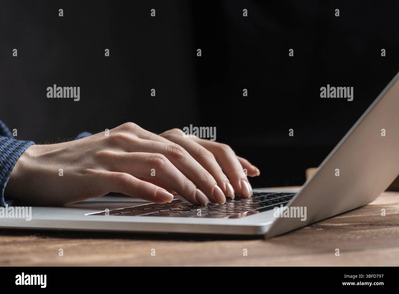 Primo piano donna con le mani appoggiate sulla tastiera del notebook. Donna d'affari che lavora con un computer alla scrivania di legno. Specialista finanziario che lavora sul posto di lavoro in ufficio Foto Stock