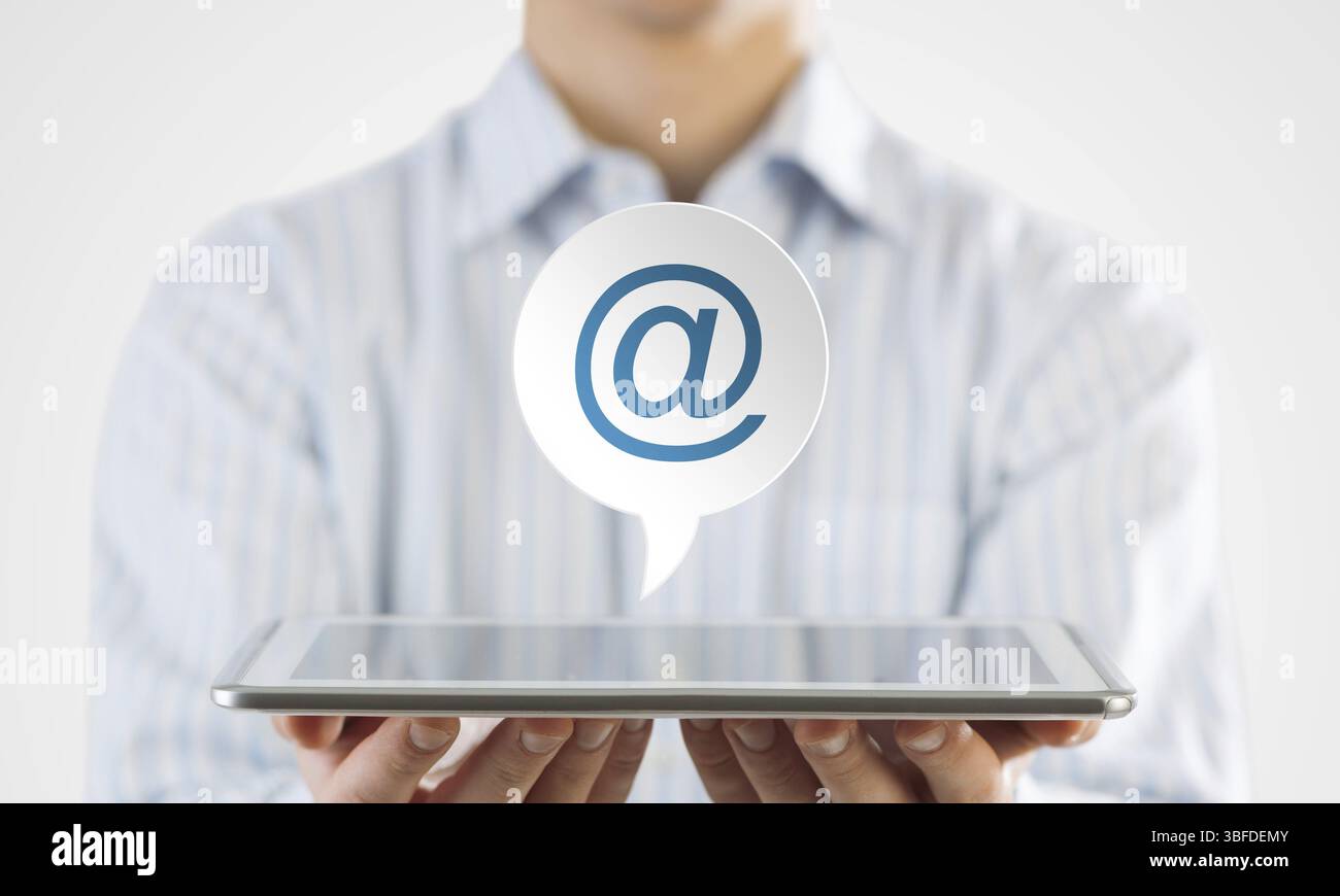 Uomo d'affari che tiene in mano il tablet con l'icona e-mail sullo schermo Foto Stock