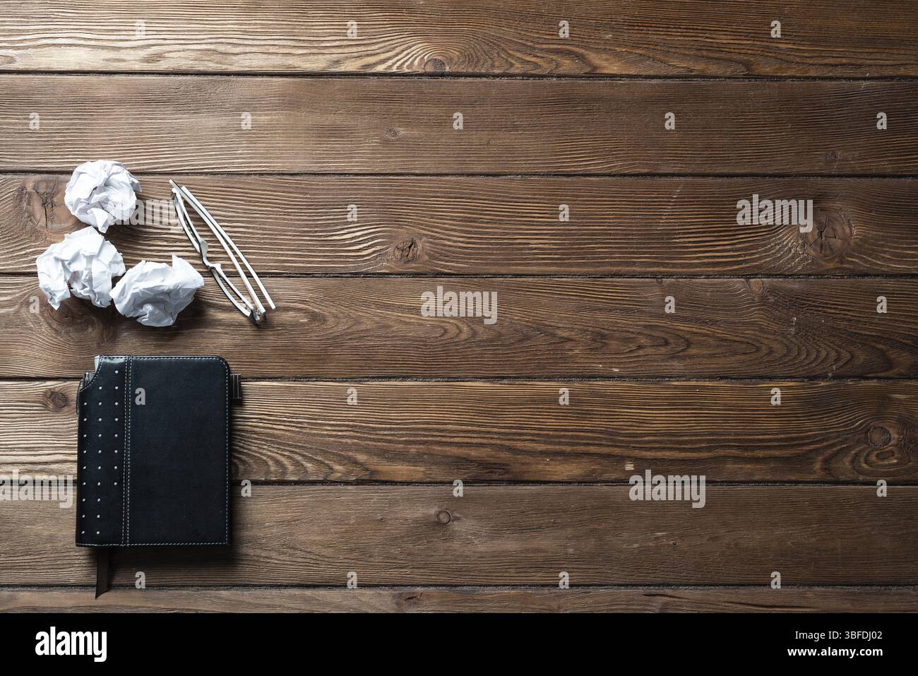 Vista superiore designer lavoro in ufficio con la carta stropicciata. Crisi di ispirazione creativa. Stabilire piani scrivania in legno con un diario e bicchieri. Idea generatio Foto Stock