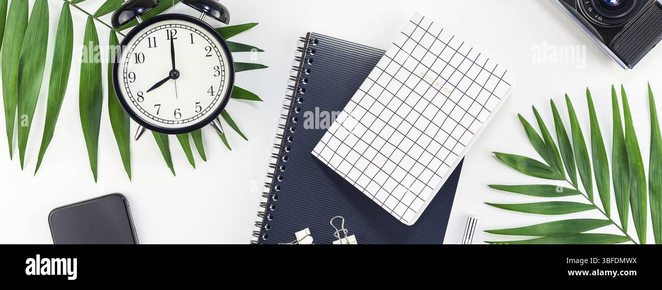 Vista superiore piana ufficio laici workspace desk design in stile forniture per ufficio sveglia tropical palm lascia la fotocamera dello smartphone spazio copia in bianco nero backgr Foto Stock