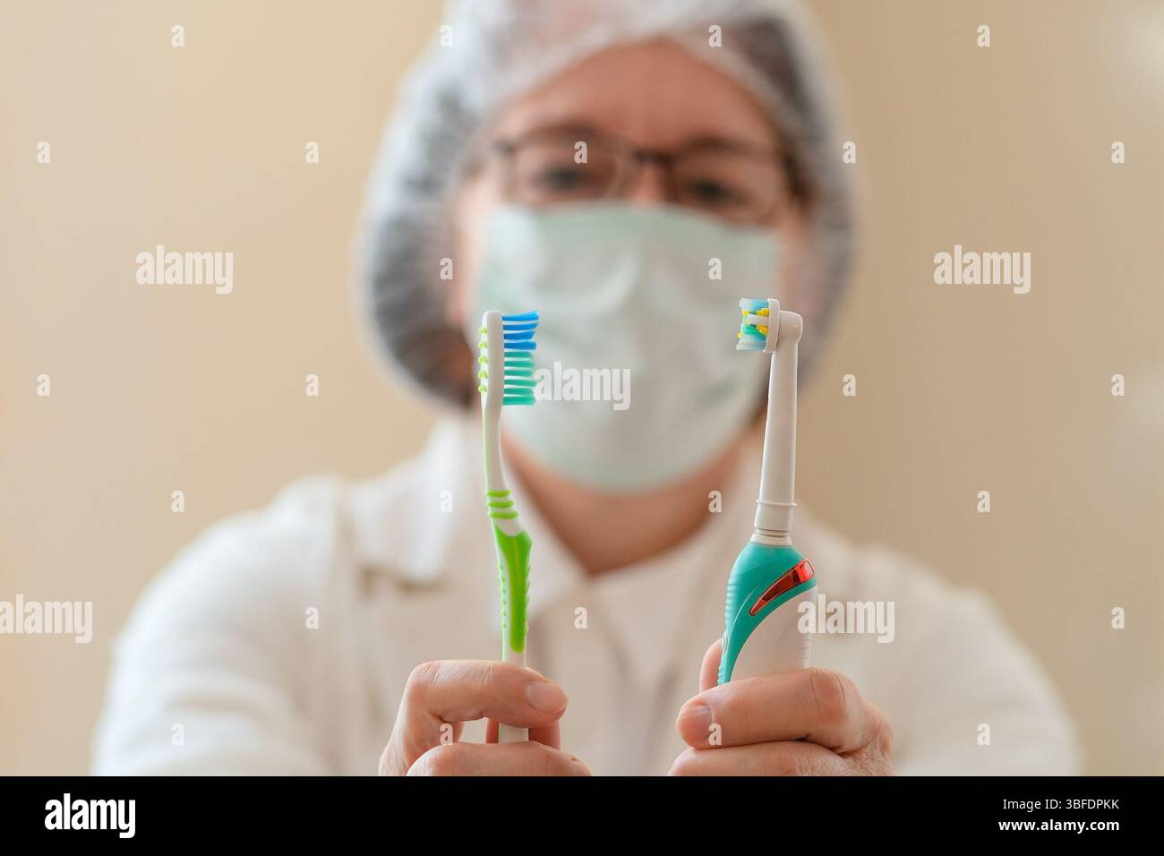 Primo piano di una dentista che tiene uno spazzolino manuale in una mano e uno elettrico nell'altra. Una guida visiva sull'igiene orale, gli strumenti dentali e il mantenimento di denti sani. Foto Stock