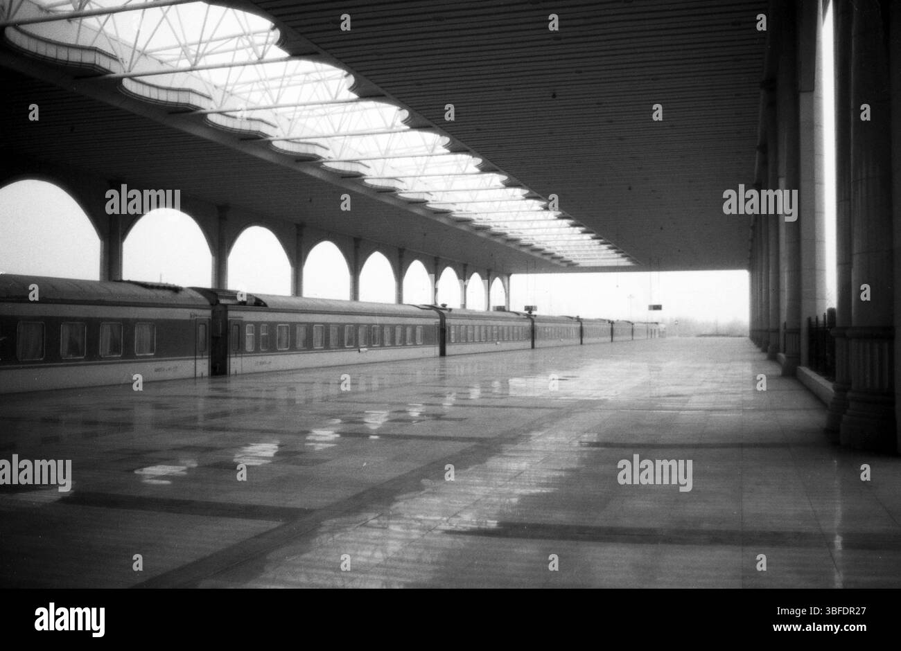 Piattaforma della stazione ferroviaria in Cina all'inizio degli anni '2010: Piattaforma vuota con tetto ad arco e treno parcheggiato, Jiangsu, Cina Foto Stock