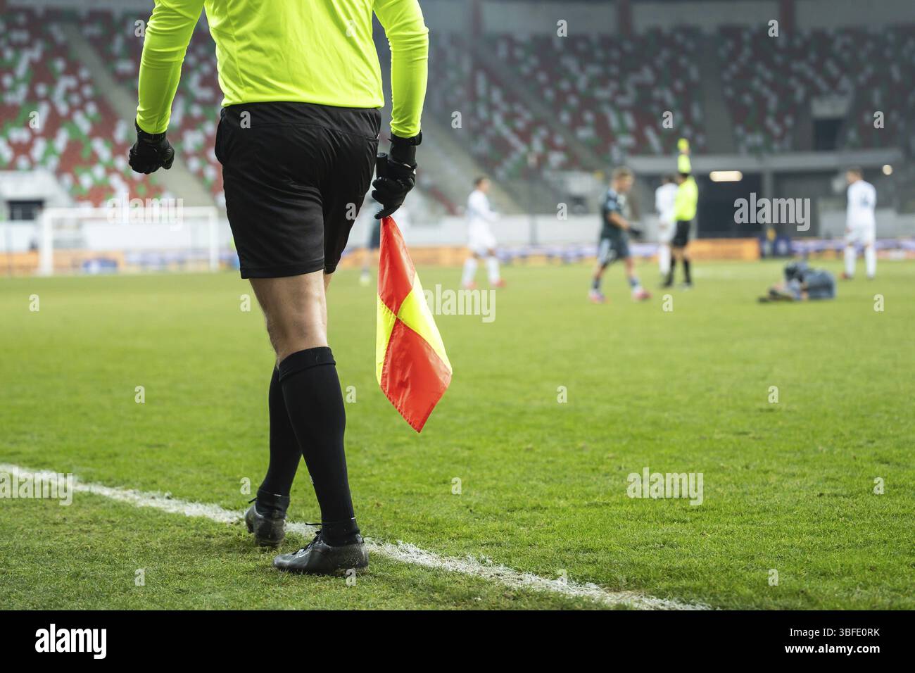 Assistente dell'arbitro di calcio durante la partita. In background l'arbitro principale dà il cartellino giallo Foto Stock
