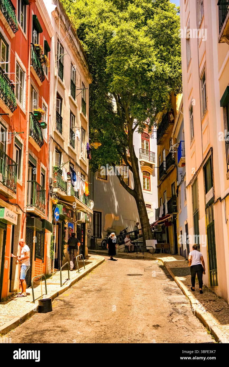 Strada stretta e ripida con tradizionali edifici colorati nella città vecchia di Lisbona, il Portogallo. Foto Stock