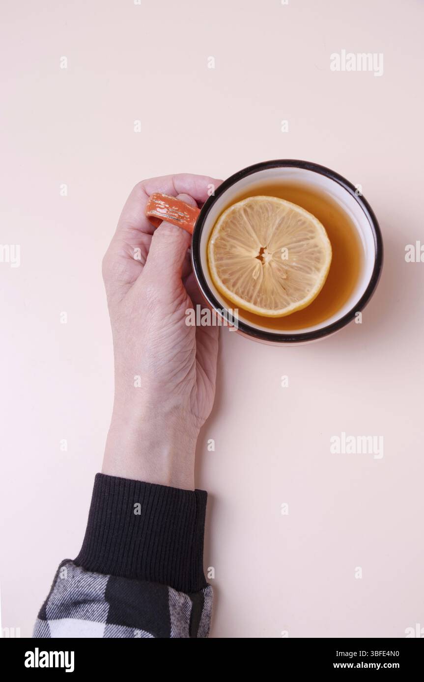 Tazza da presa femminile con tè e limone su sfondo beige, copia spazio Foto Stock
