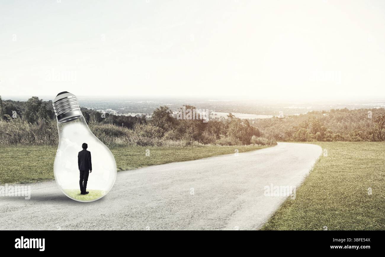 Giovane imprenditore intrappolato all'interno della lampadina della luce sulla strada di campagna Foto Stock Giovane imprenditore intrappolato all'interno della lampadina della luce sulla strada di campagna Foto Stock
