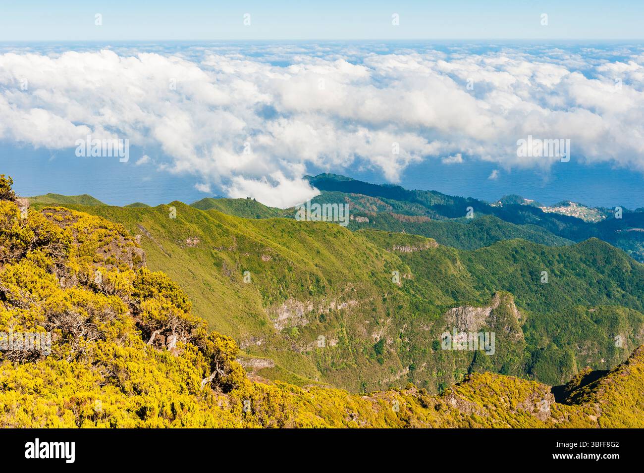 Panorama mozzafiato da un alto punto panoramico a Madeira, che rivela lussureggianti montagne verdi e soffici nuvole sull'Oceano Atlantico, mettendo in risalto il Foto Stock