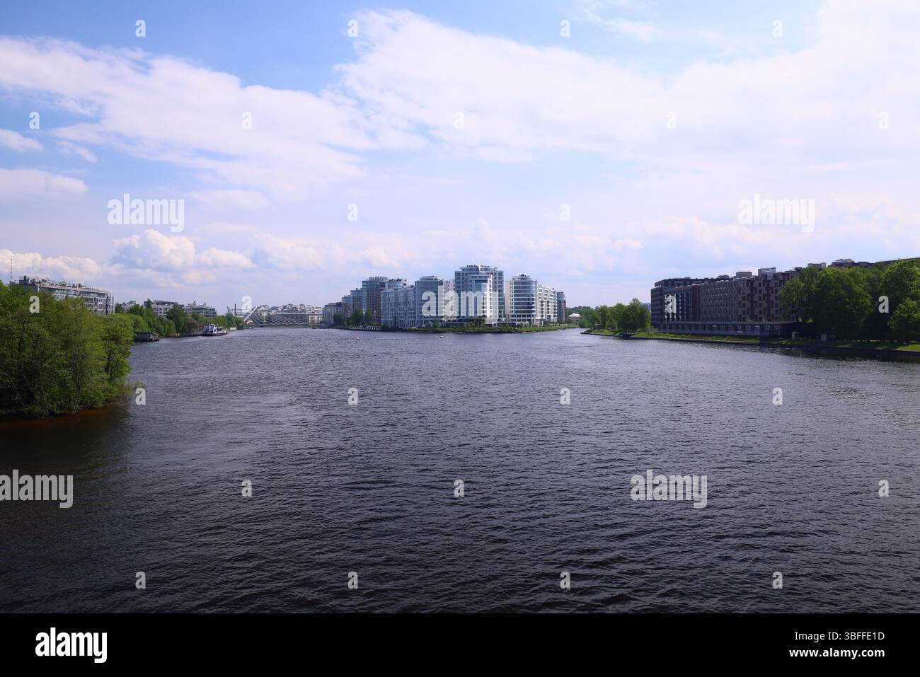 Godetevi la splendida vista sul fiume con edifici moderni e una vegetazione vivace, che fonde città e natura Foto Stock