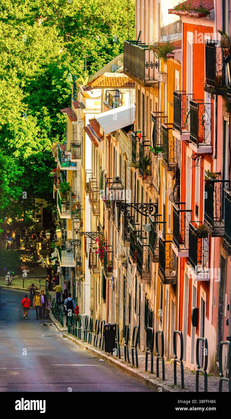 Facciate colorate e balconi in ferro battuto in una ripida strada del quartiere Bairro alto di Lisbona. Pomeriggio di sole nella capitale del Portogallo. Foto Stock