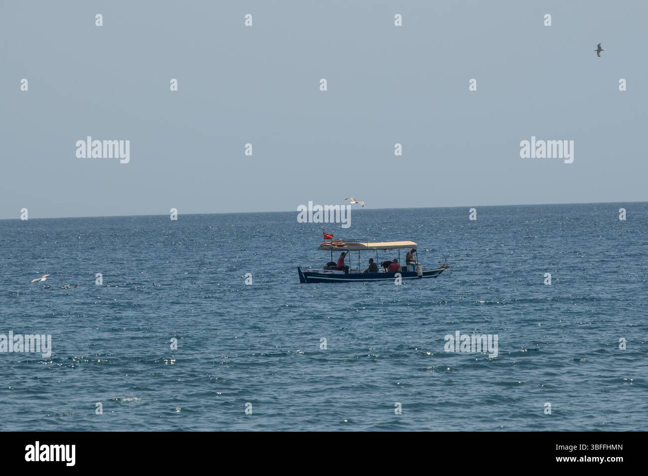 Le persone si godono una rilassante gita di pesca di un giorno su un'affascinante barca locale, mentre un elegante catamarano naviga più lontano, catturando l'essenza di diversi marine Foto Stock