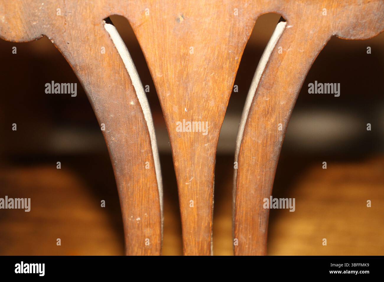 Primo piano dello schienale di una sedia in legno, con particolare attenzione alle spranghe verticali dello schienale. Il design comprende tre elementi verticali con bordi interni curvi. Foto Stock