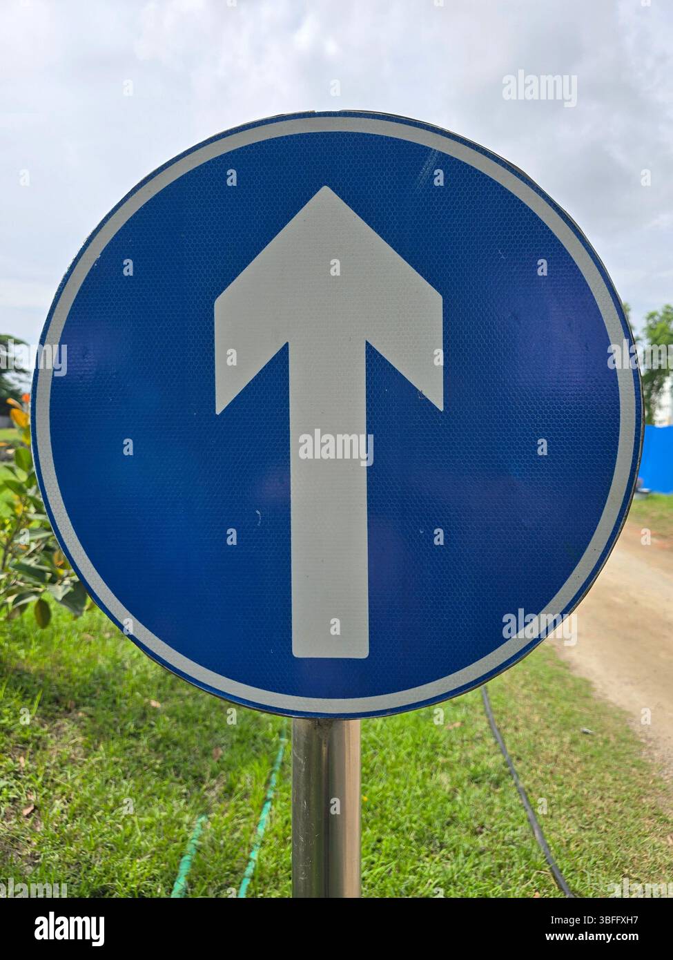 Rotondo con segnaletica stradale blu con freccia bianca a sinistra - Immagine stock catturata con smartphone