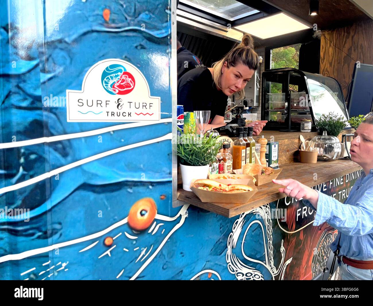 Street food Surf&Turf Truck dipendente che offre cibo ai clienti durante una festa in giardino a Sofia, Bulgaria, Europa orientale, Balcani, UE - Immagine stock catturata con smartphone