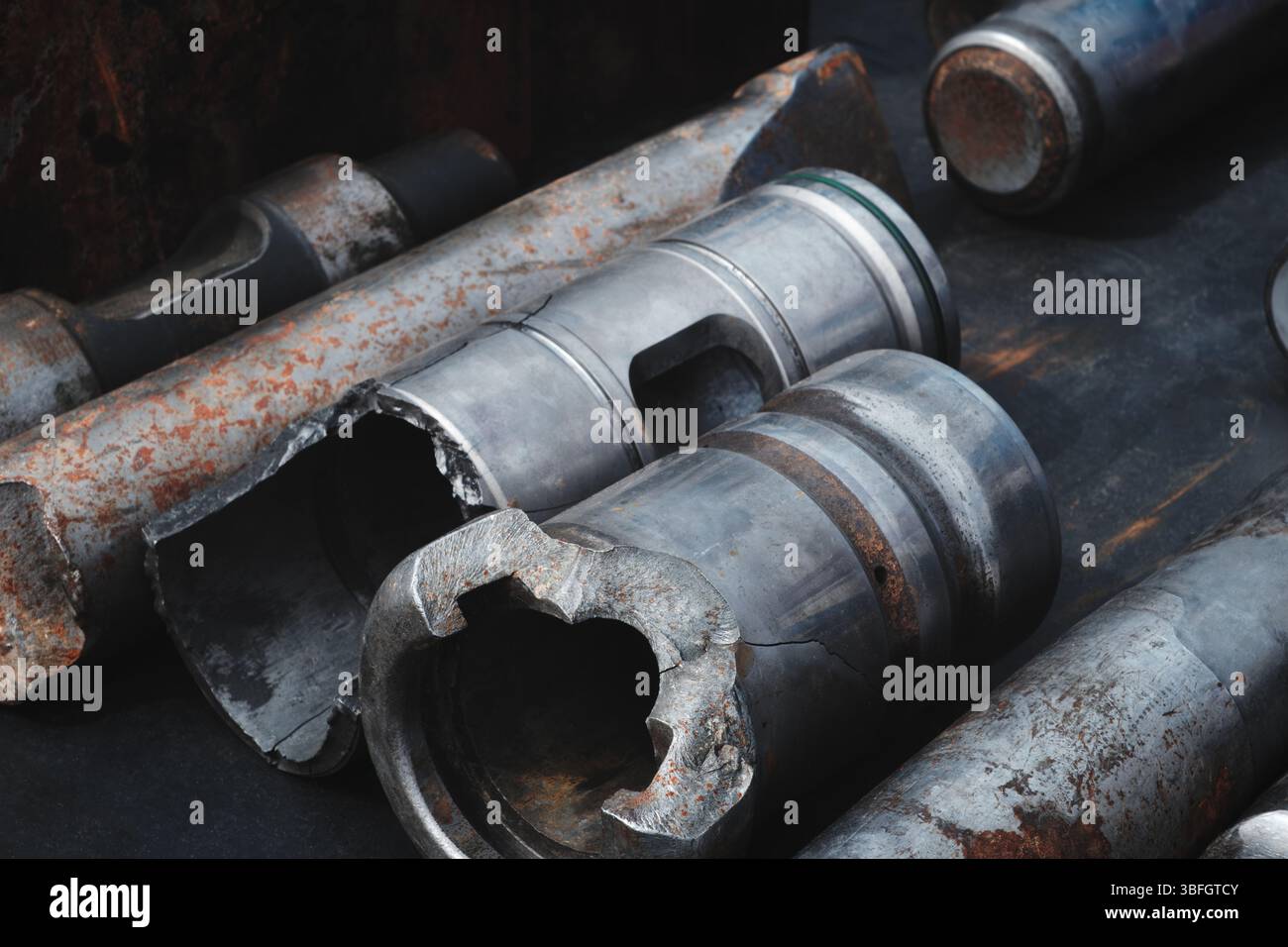 Un mucchio di pezzi metallici arrugginiti, tra cui un tubo rotto e un tubo piegato. La scena è una scena di decadenza e abbandono del concetto industriale Foto Stock