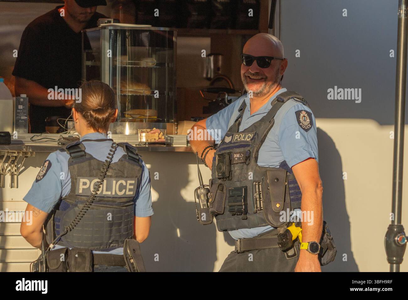 Kununurra Australia - 11 maggio 2025; due poliziotti in uniforme, un maschio e una femmina al carrello del caffè. Foto Stock