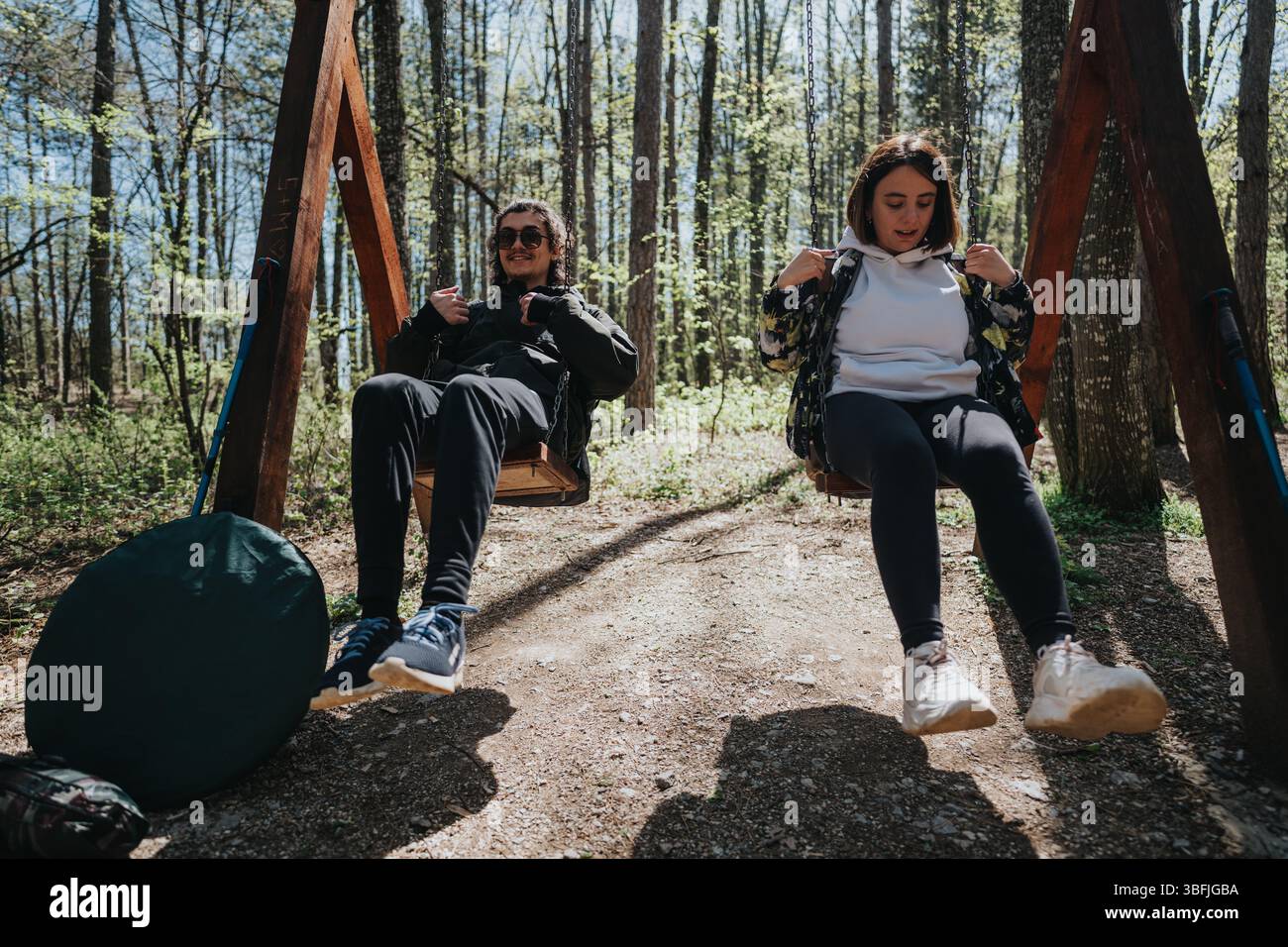 Coppia che si gode un momento rilassante sulle altalene in una foresta serena Foto Stock