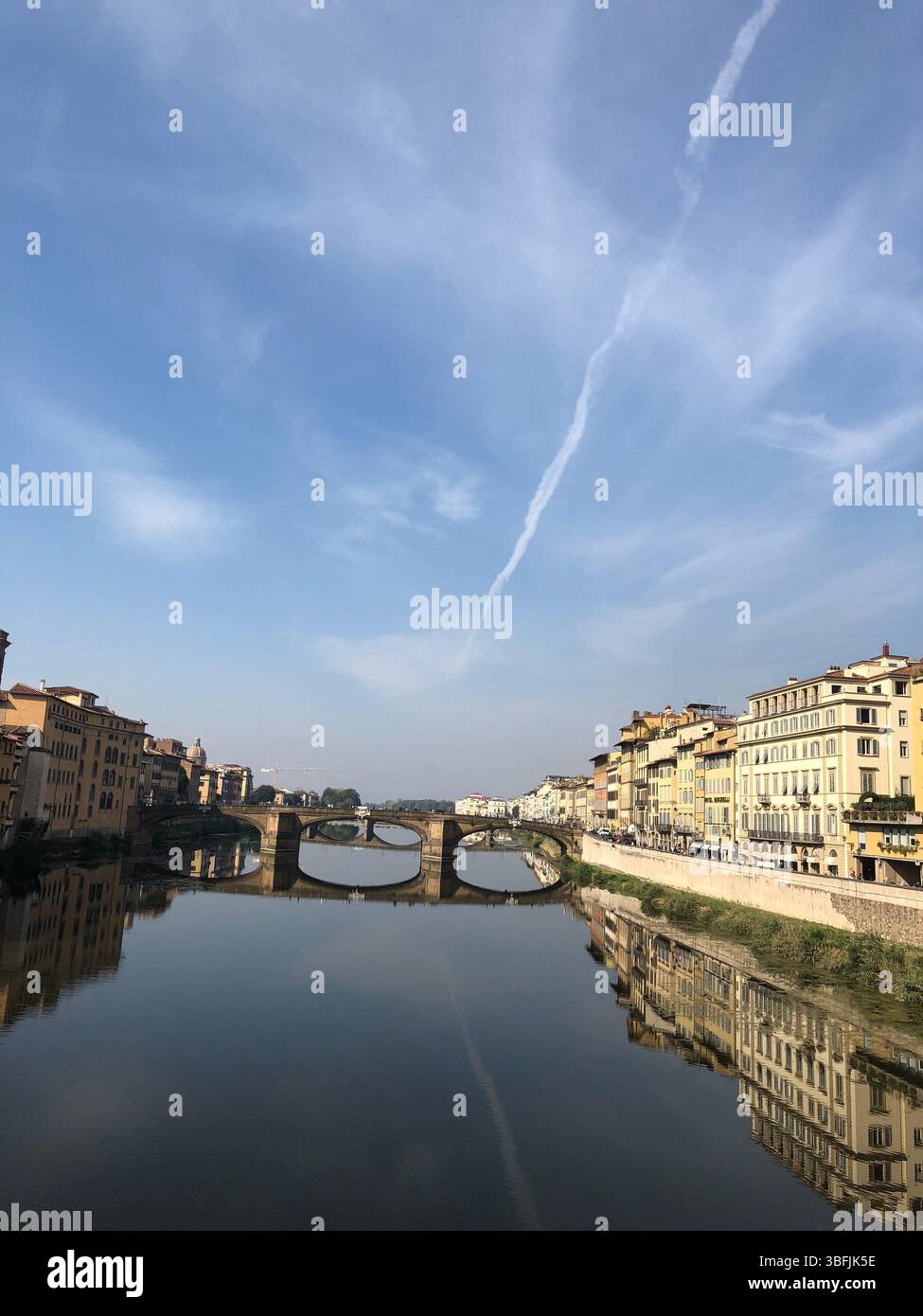 Il fiume Arno con riflessi di edifici storici e un ponte in pietra a Firenze, Italia, fotografato in una limpida giornata d'autunno. Foto Stock