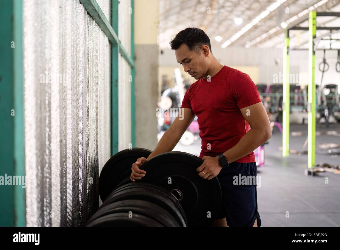 Fitness e allenamento di forza. Un giovane che solleva pesi in palestra. Foto Stock