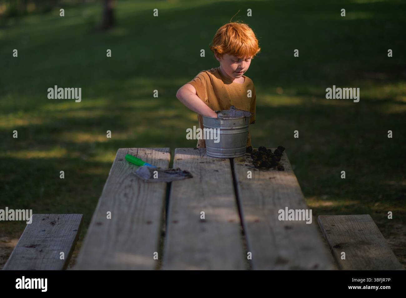 Semplice scena d'infanzia di ragazzo che colleziona lumache nel parco estivo Foto Stock