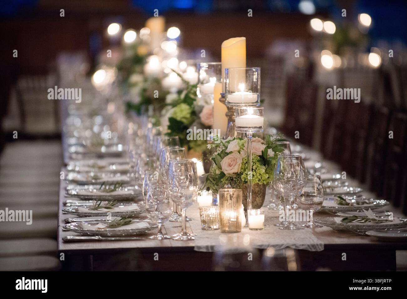 Elegante tavolo da ricevimento a lume di candela con fiori e bicchieri Foto Stock