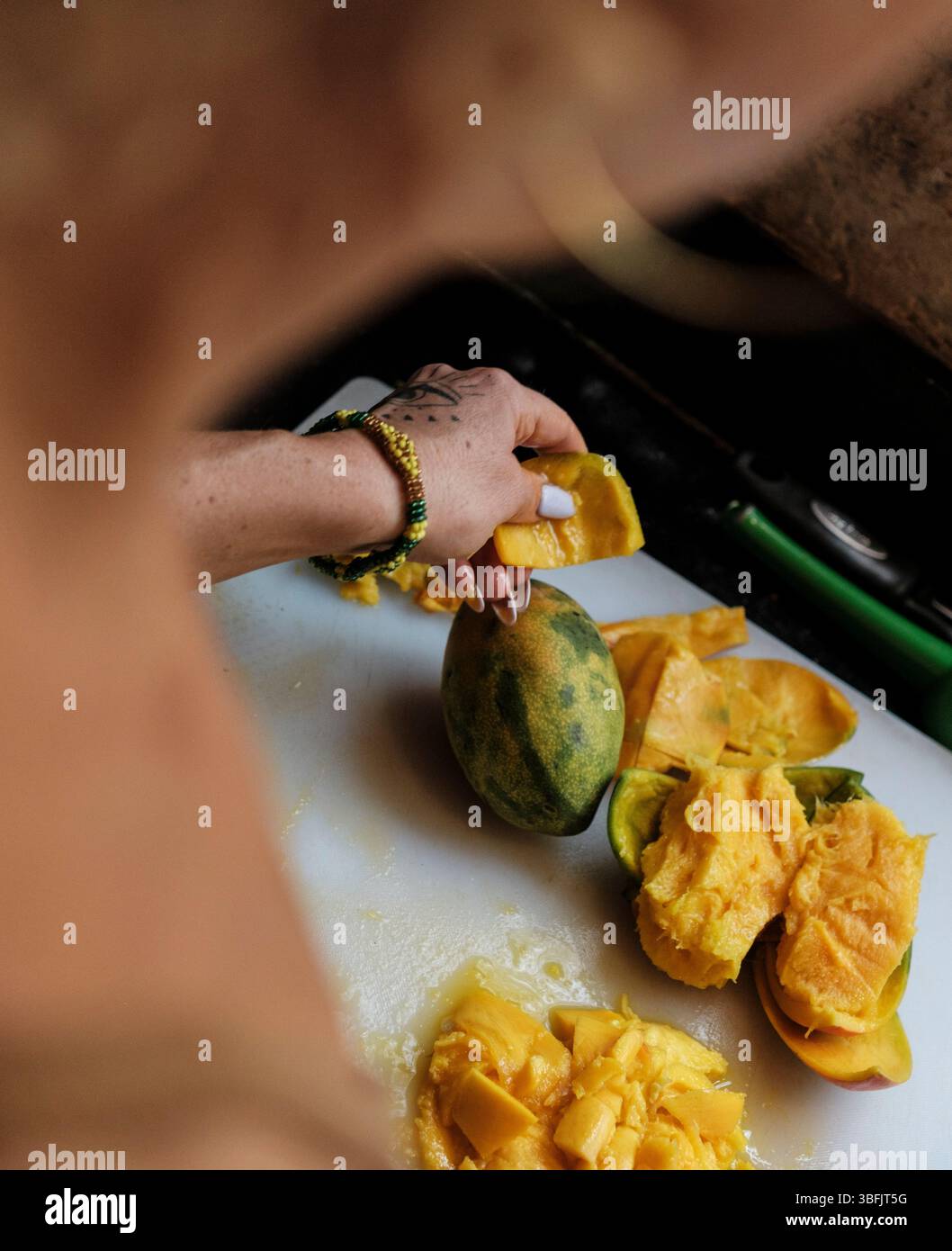 Donna che prepara il mango fresco sul tagliere Foto Stock