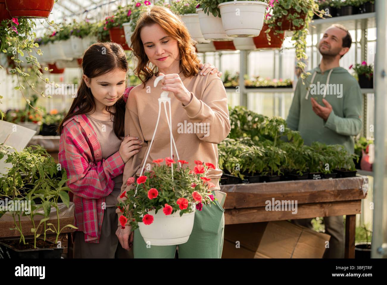 Famiglia che ama il giardinaggio insieme in una serra Foto Stock