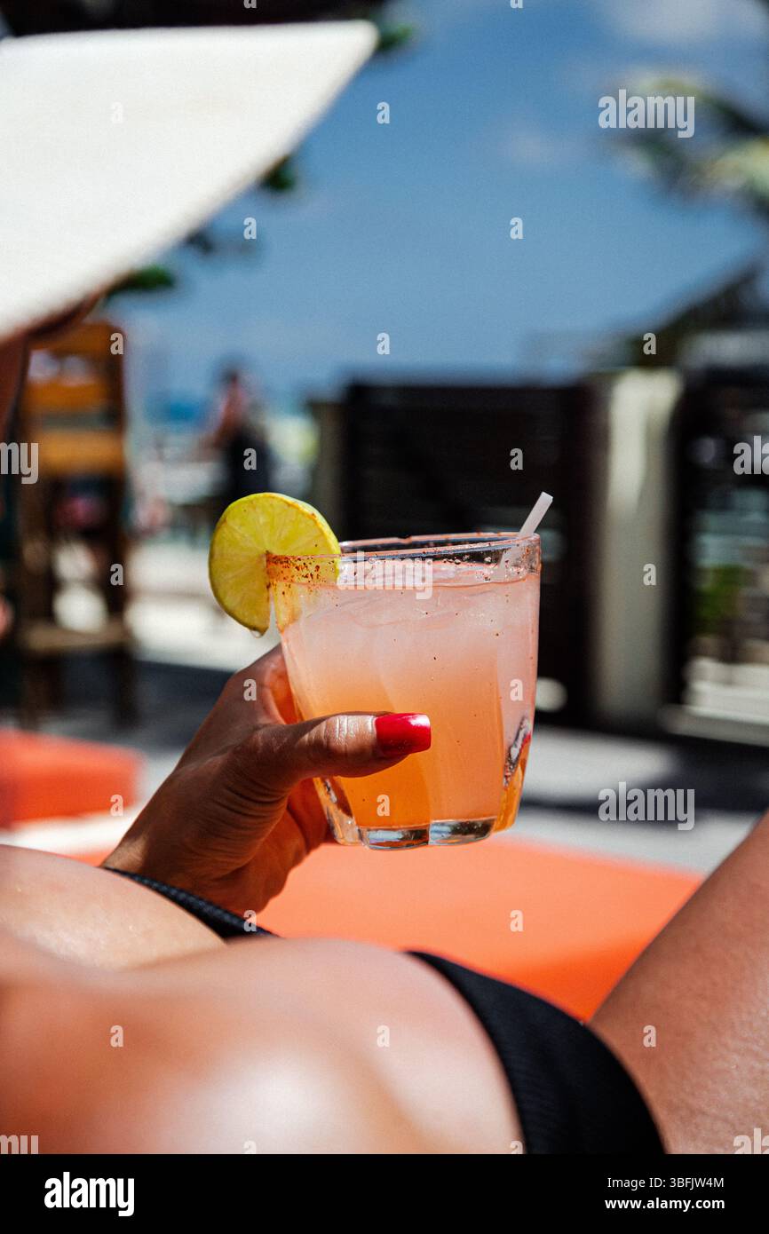 Donna che si rilassa a bordo piscina con cocktail di agrumi al sole del Belize Foto Stock