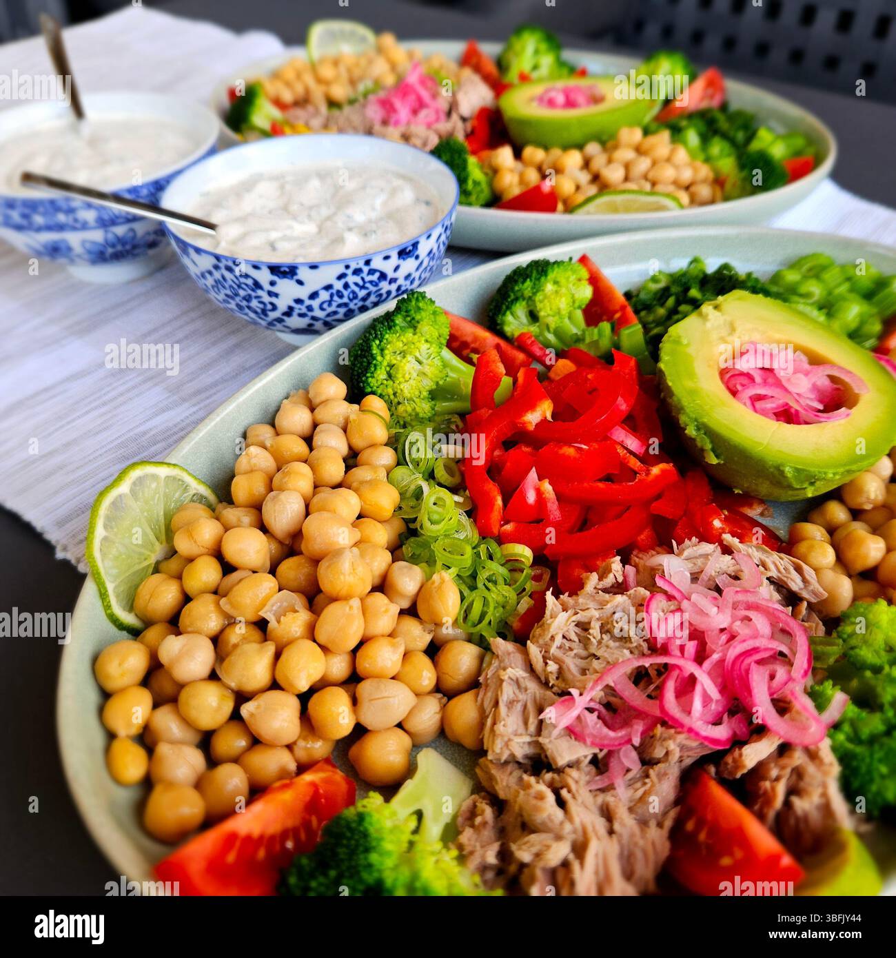 piatto sano di ceci avocado tonno peperone broccoli pomodori cipolle e salsa di panna acida alle erbe Foto Stock