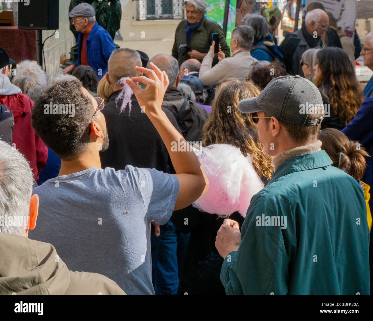 Due uomini mangiano caramelle di cotone all'fête de la commune di Parigi. Foto Stock