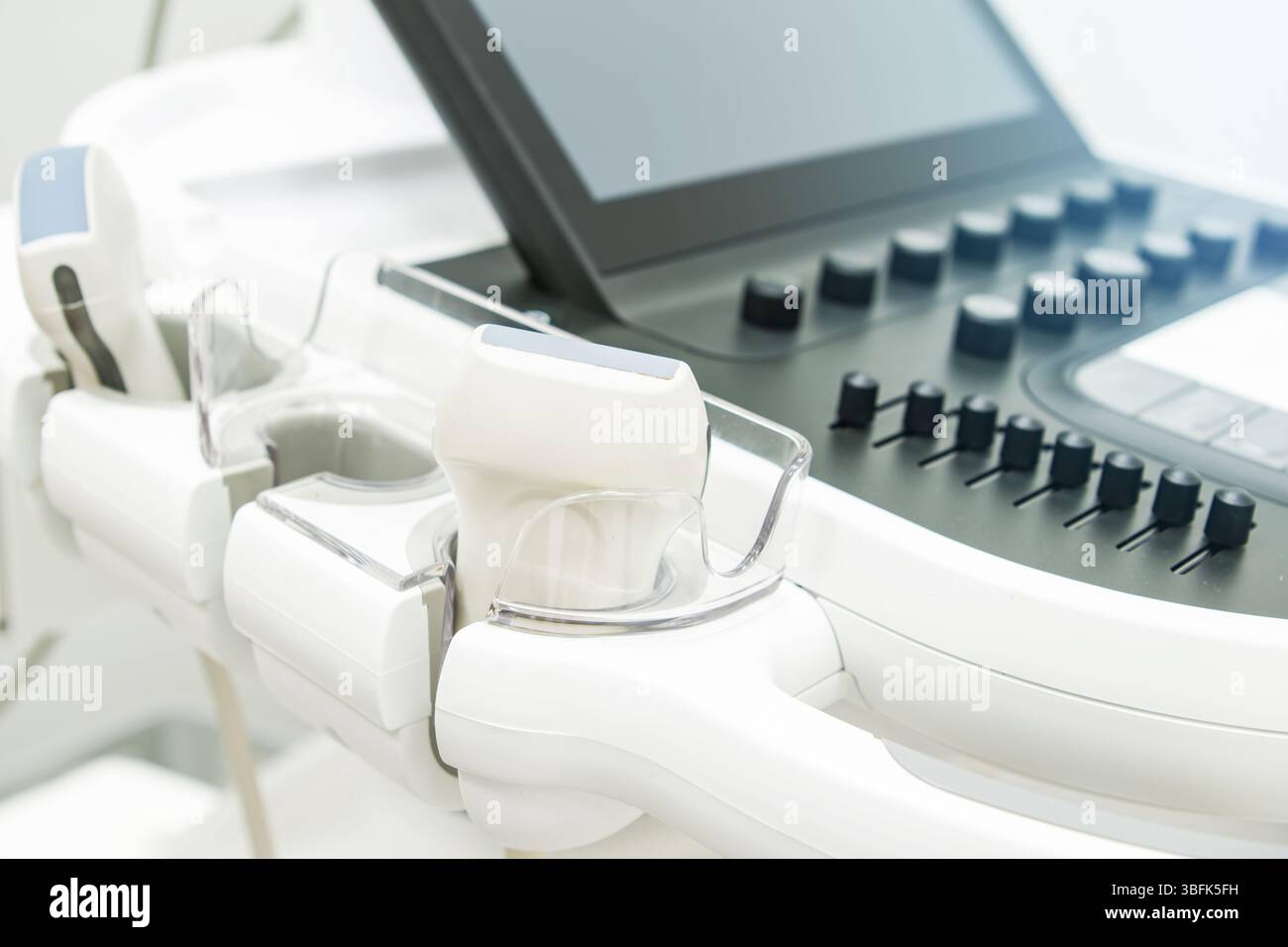 Macchina a ultrasuoni ad alta tecnologia con comandi e apparecchiature digitali in una sala esame pulita e luminosa, pronta per l'uso sul paziente e per la diagnostica. Foto Stock