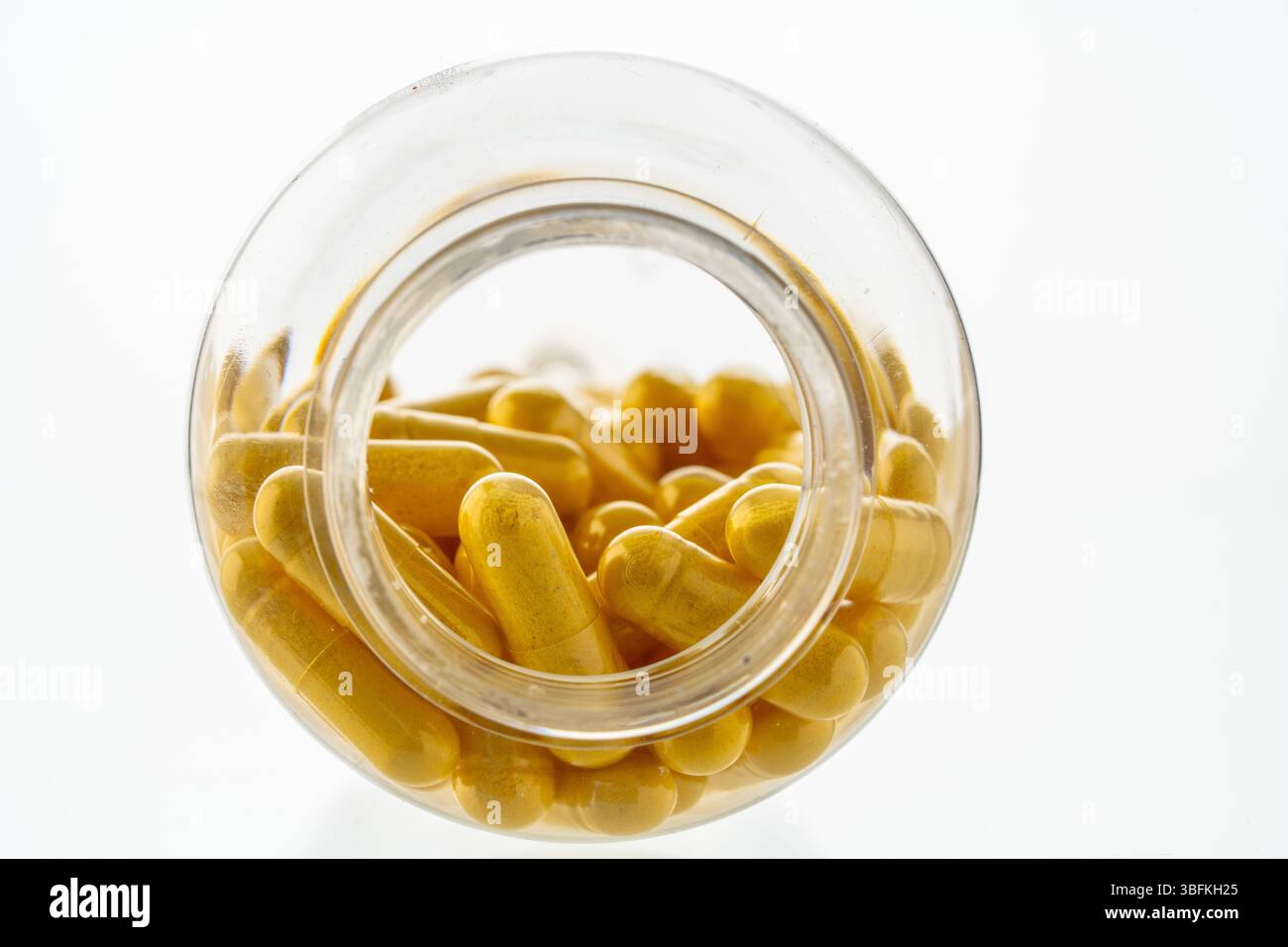 Un vaso con le pillole all'interno giace su uno sfondo bianco. Acido ialuronico, collagene, vitamine o mirtillo per perdere peso. Preparazioni mediche per la salute Foto Stock