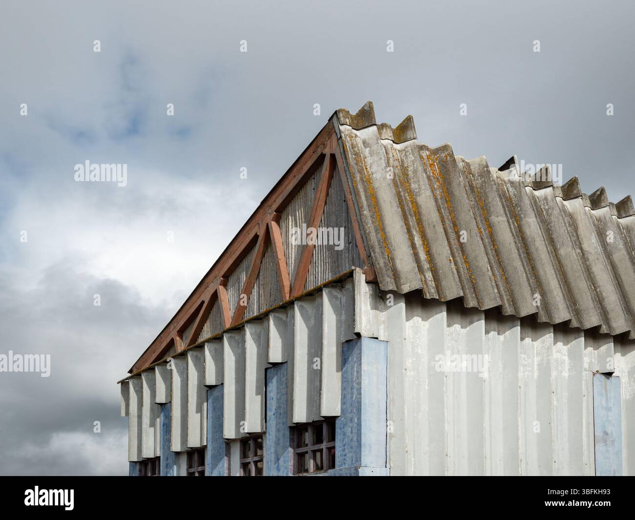 Dettagli architettonici ravvicinati di un edificio industriale in disuso con tetto e facciata in cemento con colonne di colore a contrasto Foto Stock