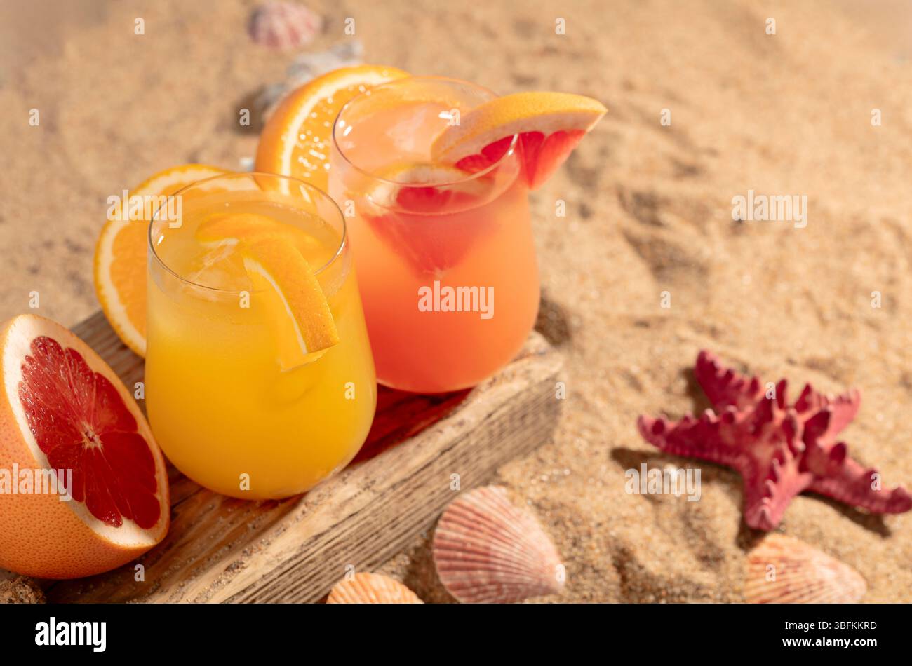 Cocktail di pompelmo e arancia con ghiaccio su una vecchia tavola di legno. Bevande rinfrescanti in spiaggia. Foto Stock