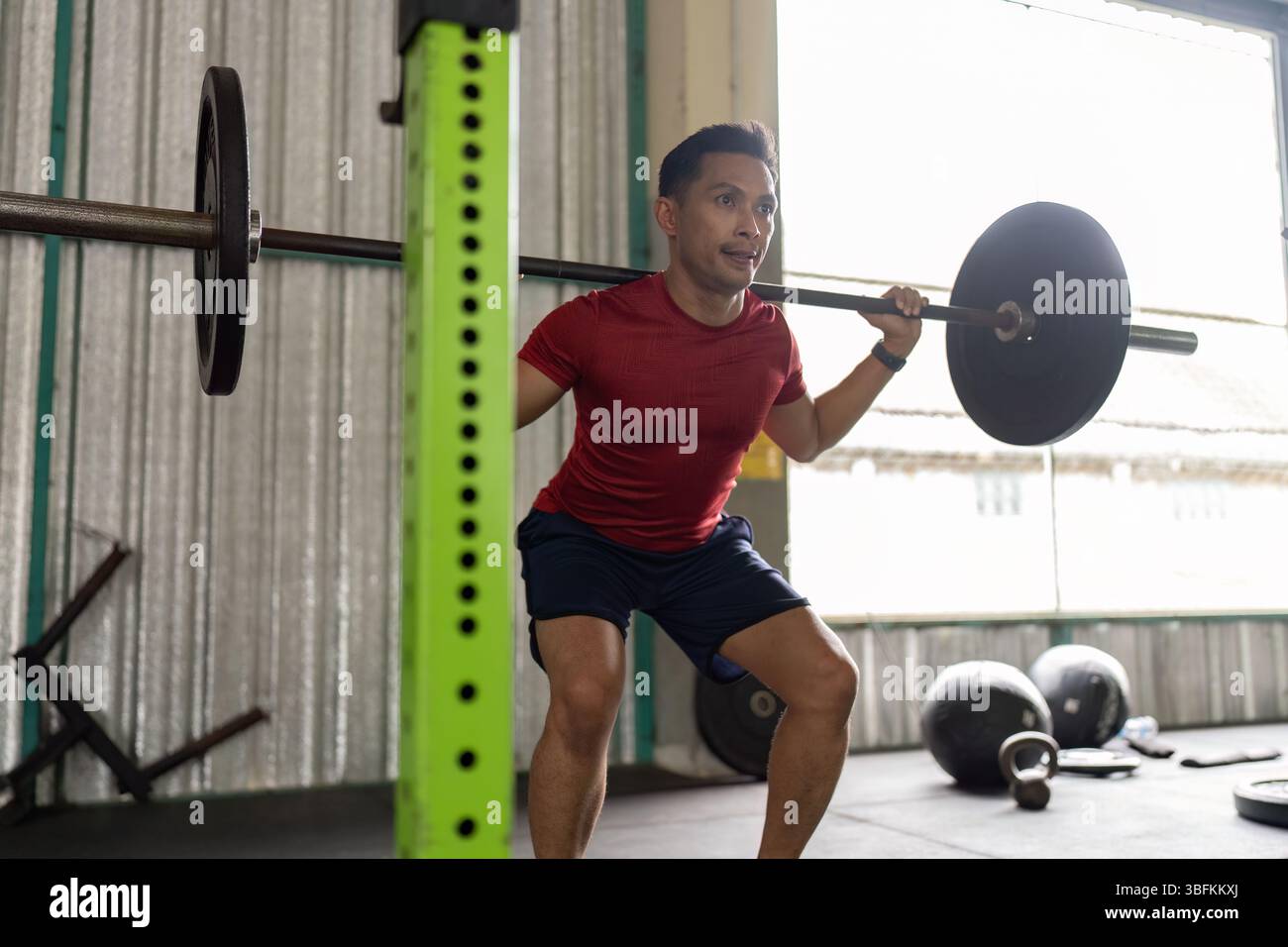 Allenamento di forza. Giovane che esegue squat con barbell in palestra. Foto Stock