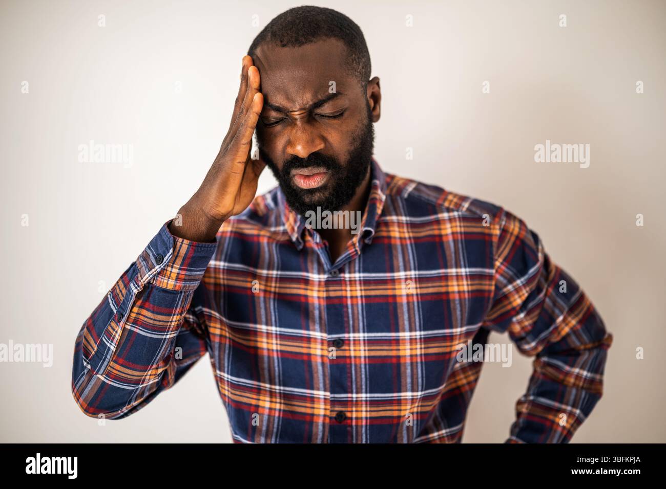 Ritratto di un uomo nero ansioso e con mal di testa. L'uomo adulto è stanco e sovraccarico di lavoro. Foto Stock