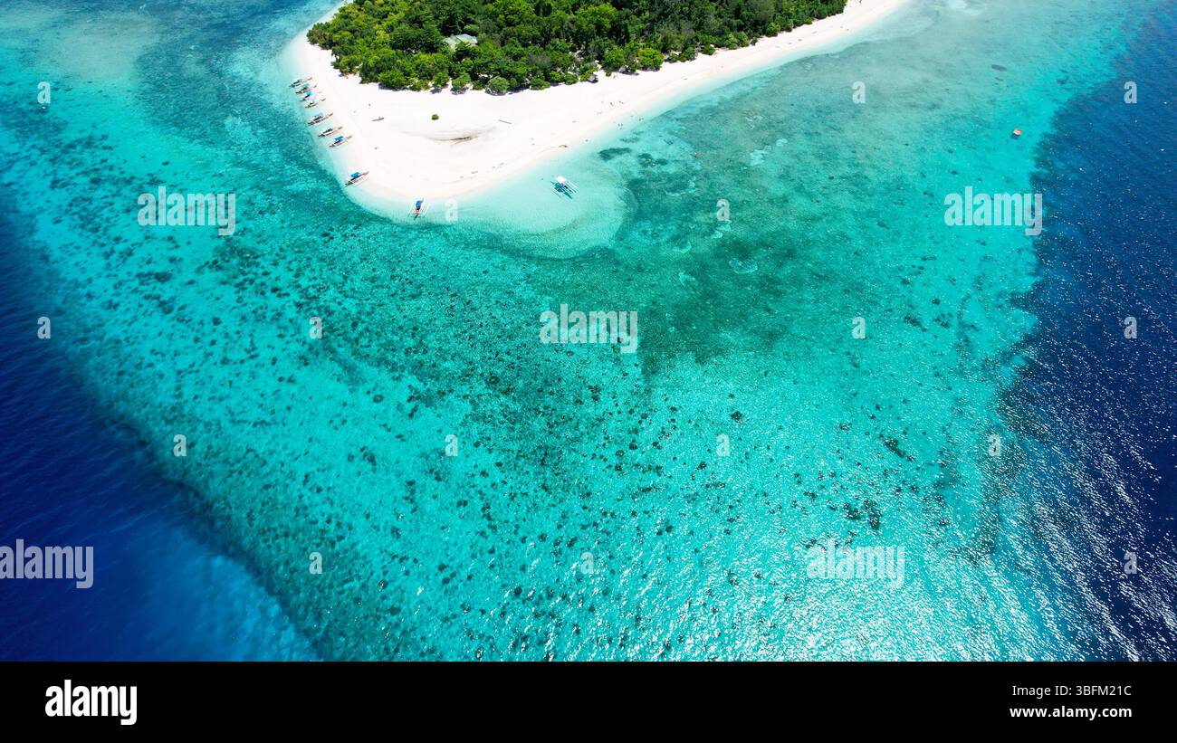 Spettacolare vista aerea della vibrante barriera corallina, delle acque turchesi e di una barra di sabbia bianca al largo della remota isola di Mantigue nelle Filippine. Foto Stock
