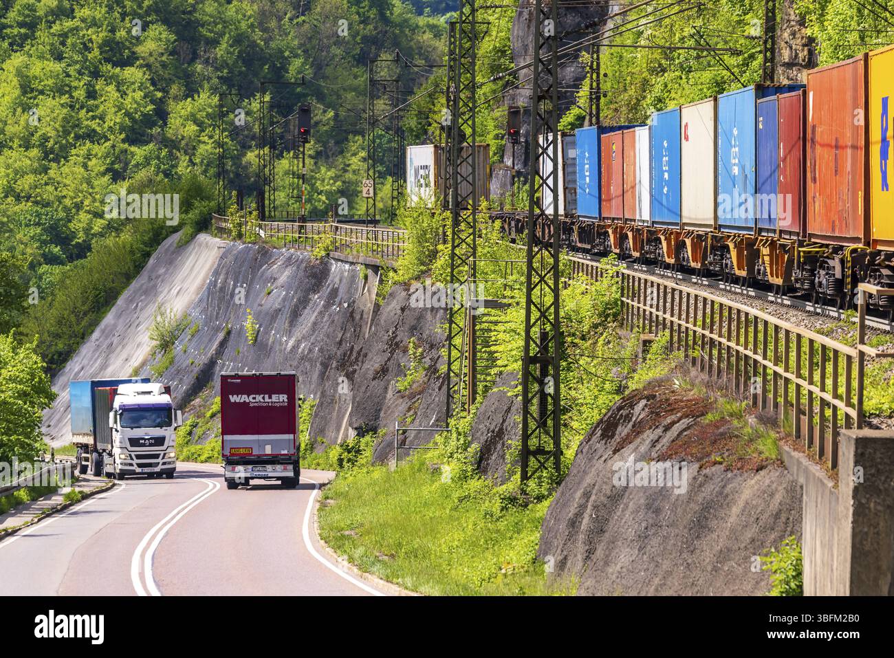 Treno merci che viaggia sulla tortuosa linea ferroviaria Geislinger Steige. Paesaggio lungo la linea ferroviaria in primavera. Amstetten, Baden-Wuerttemberg, Germa Foto Stock