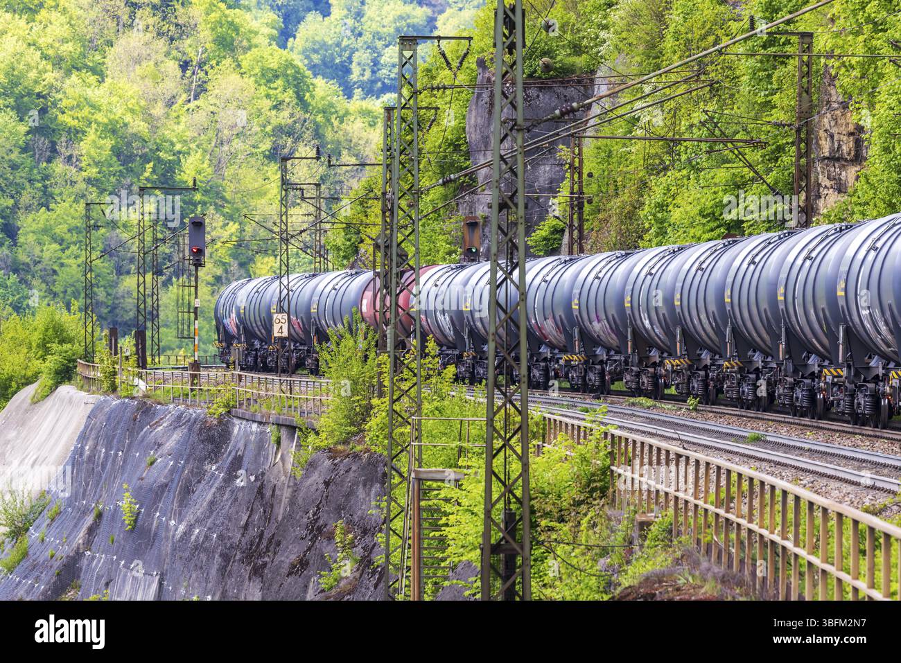 Treno merci che viaggia sulla tortuosa linea ferroviaria Geislinger Steige. Paesaggio lungo la linea ferroviaria in primavera. Amstetten, Baden-Wuerttemberg, Germa Foto Stock