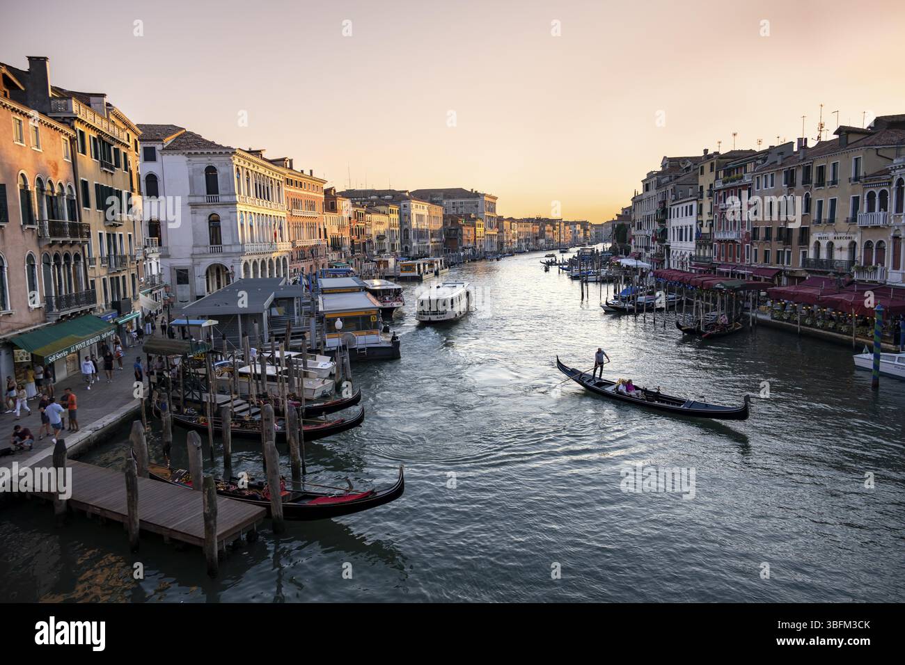 Vista sul Canal grande con gondolieri al tramonto, atmosfera serale pittoresca con palazzi sul canale, vista dal Ponte di Rialto, Venezia, Veneto, i Foto Stock