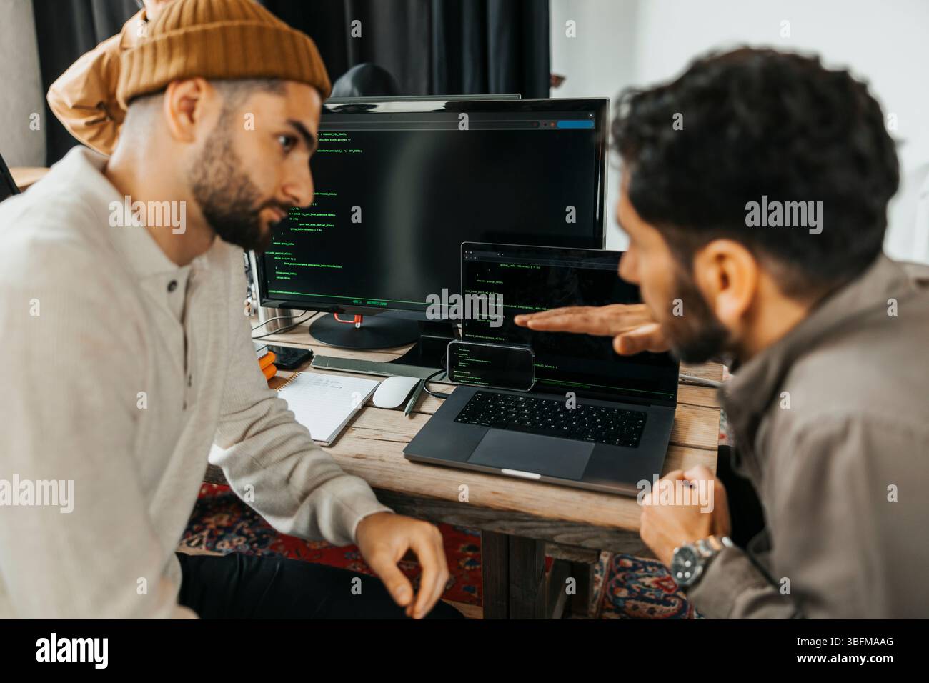 Programmatore di computer maschio che spiega i codici binari al collega in ufficio Foto Stock