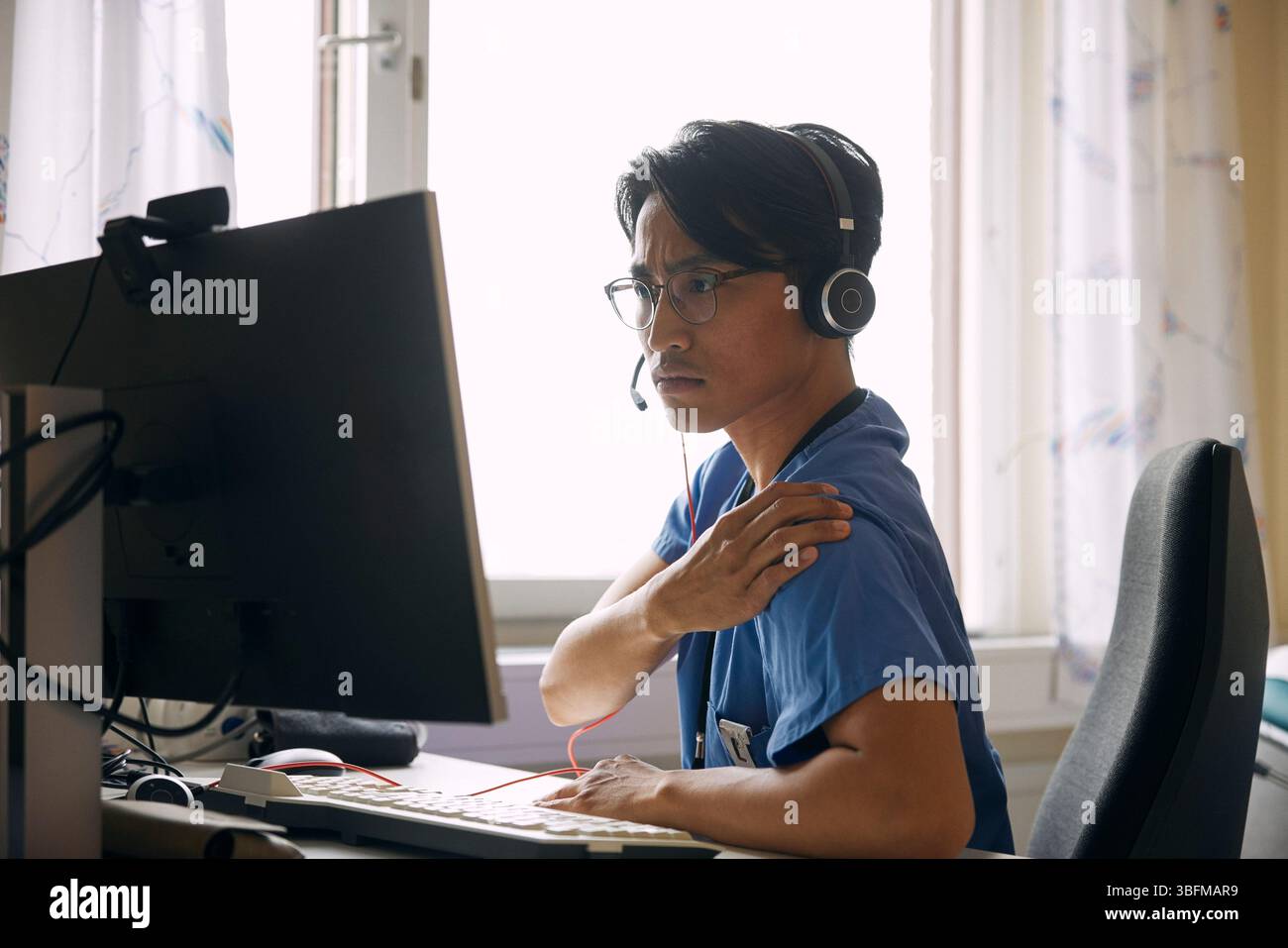 Medico che indossa l'auricolare e spiega durante una videochiamata sul computer Foto Stock