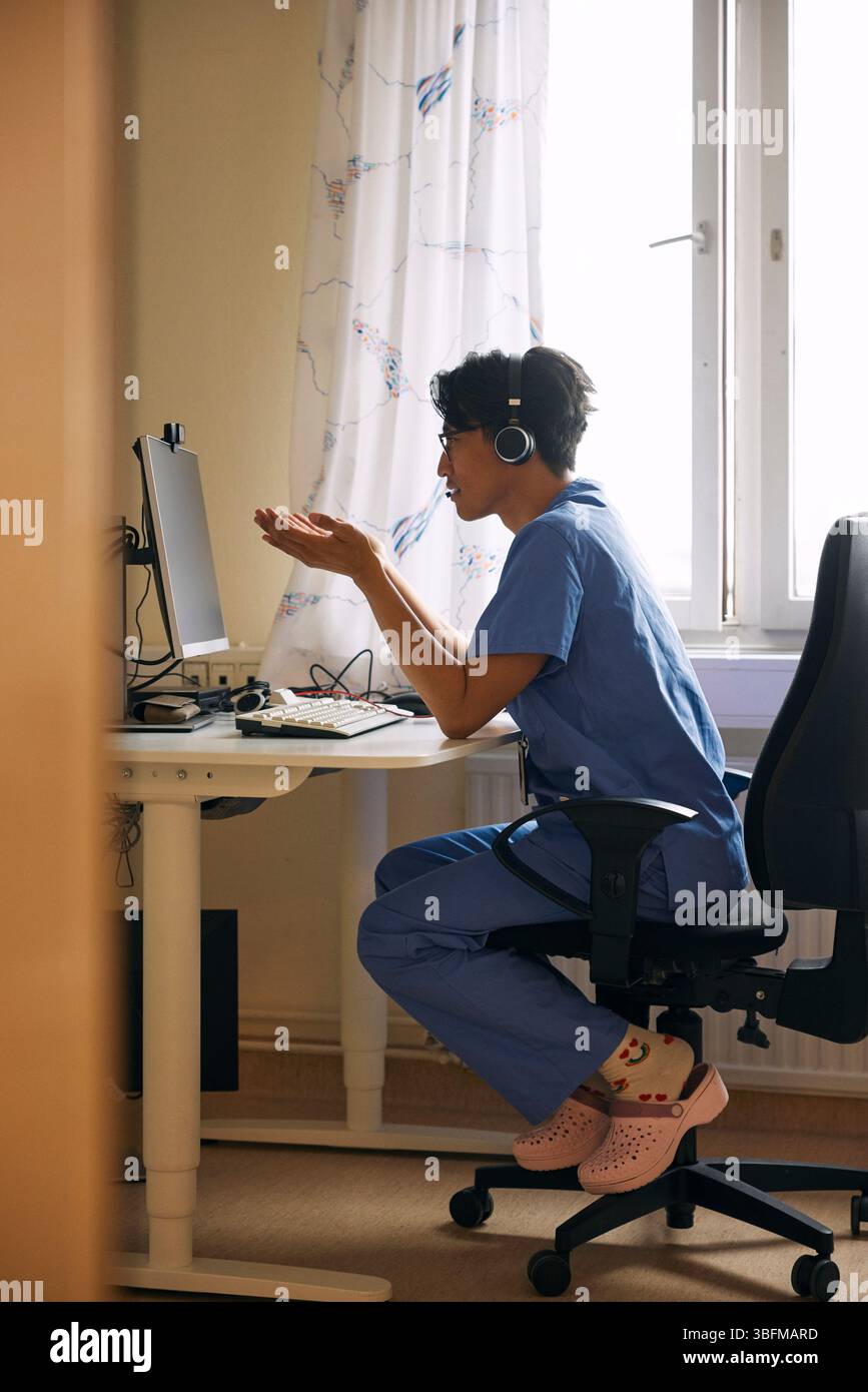 Medico che ha parlato in videochiamata alla reception della clinica Foto Stock