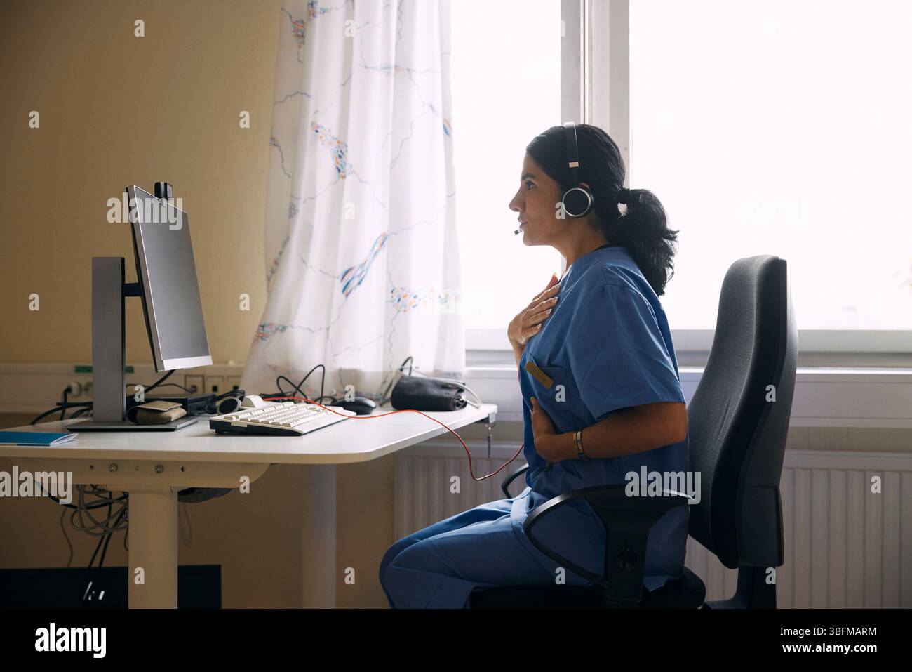 Medico donna che spiega durante una videochiamata al computer in clinica Foto Stock