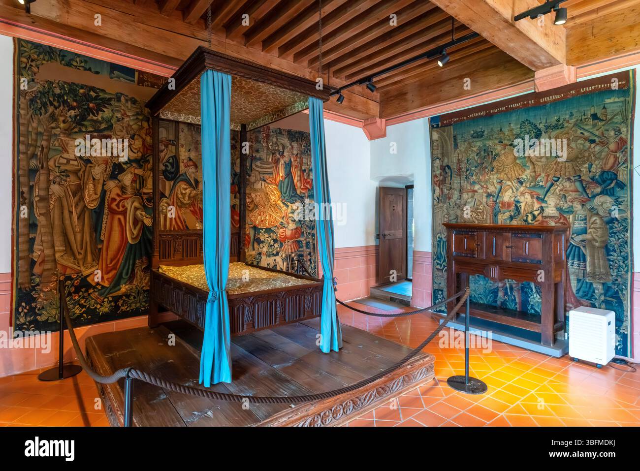 La camera da letto principale del castello di Gruyères è decorata sontuosamente con arazzi colorati e un piccolo letto a baldacchino. Cantone di Friburgo, Svizzera. Foto Stock